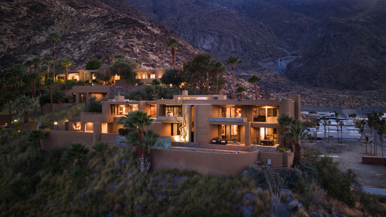 Estate exterior at dusk, lit against the mountainside