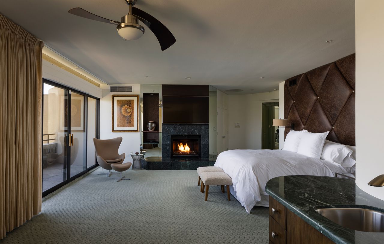 Primary suite with tufted leather headboard and marble fireplace